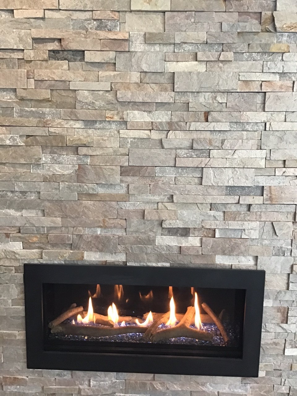 Front on View of a fireplace clad in Norstone Sierra XLX Silver Grey Stacked Stone